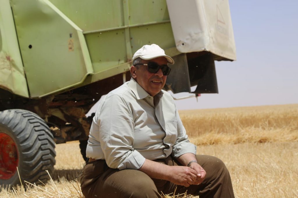 وزير الزراعة مبتسما خلال موسم حصاد القمح في مشروع غرب المنيا